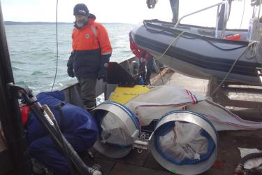 Harvey Walsh inspecting sampling gear, bongo nets, and zodiac on deck.