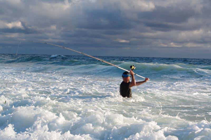 A recreational angler casts a line in the surf.