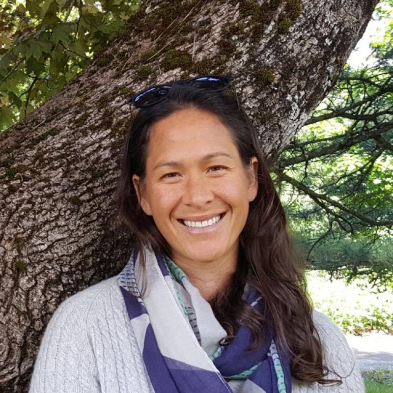 Photo of Tia Brown leaning against a large tree