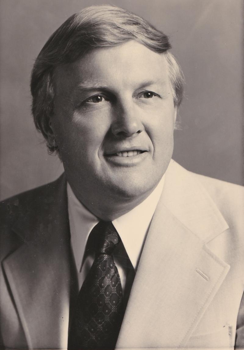 black and white portrait of a smiling man wearing a suit and tie