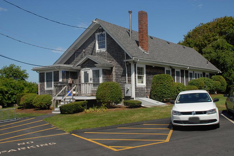 close-up color photo of the cottage from the parking lot, car in front, as it appears today
