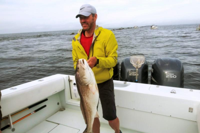 A man standing on a fishing boat holding a fish.