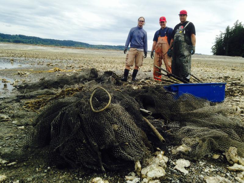 Blair Paul and two colleagues stand in front of derelict nets prior following a beach clean up. 