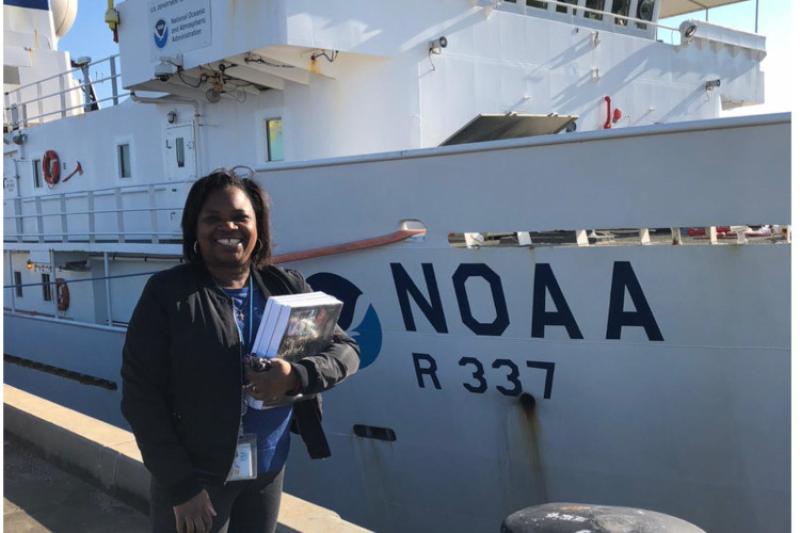 LaGena standing in front of NOAA Ship Okeanos Explorer while it is docked.