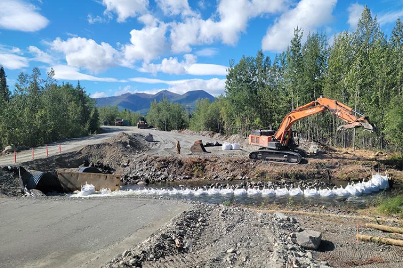 Construction equipment alongside a stream near a road