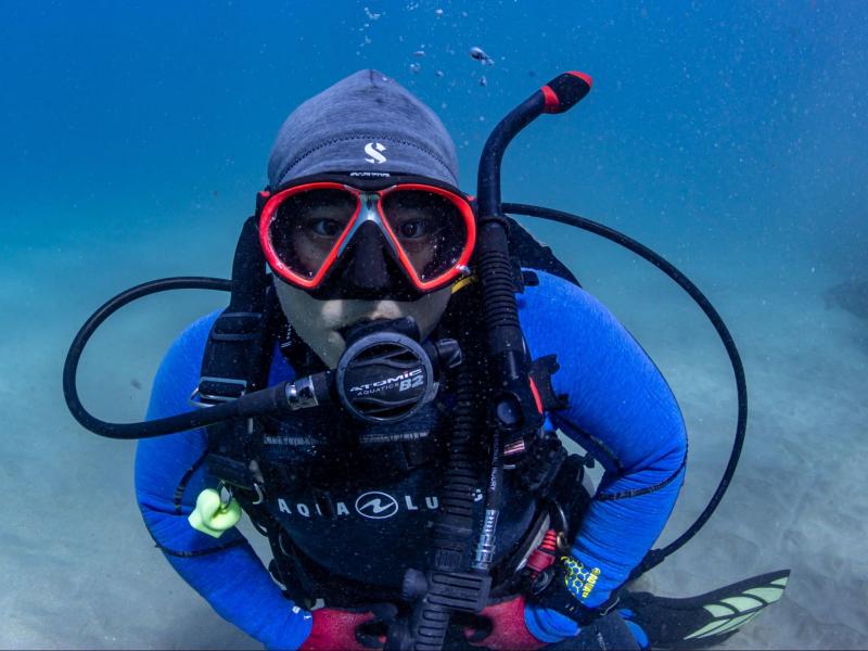 A scuba diver looks at the camera from under the water