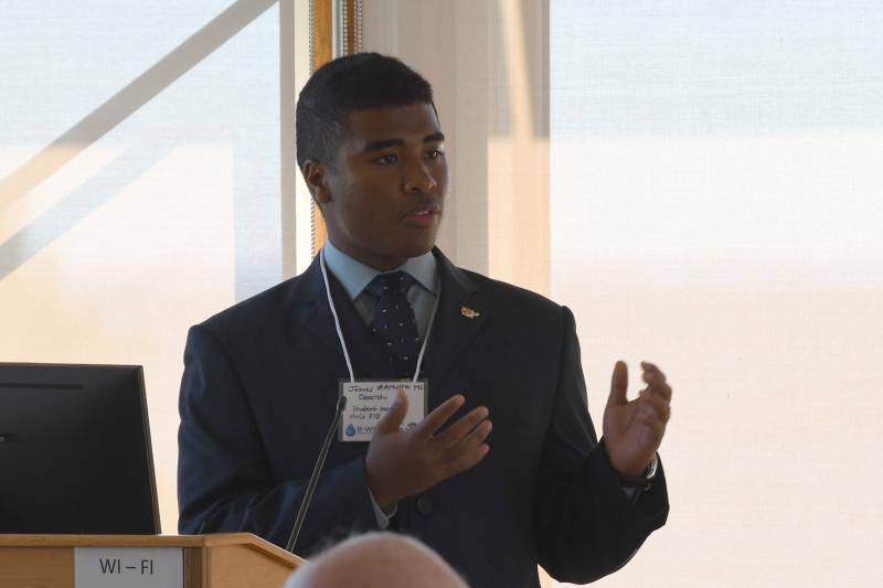 A high school student gestures as he speaks at a podium