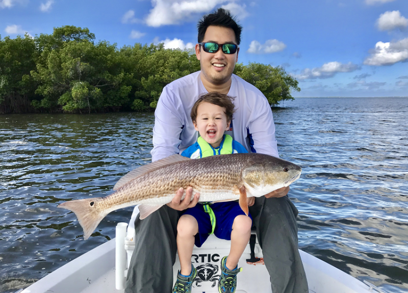 Anglers display a redfish from a boat.
