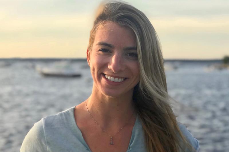 Angela Silva poses in front of a water body filled with boats.