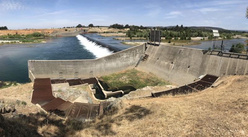 Dam and concrete fish ladder in a dry, gold, California landscape