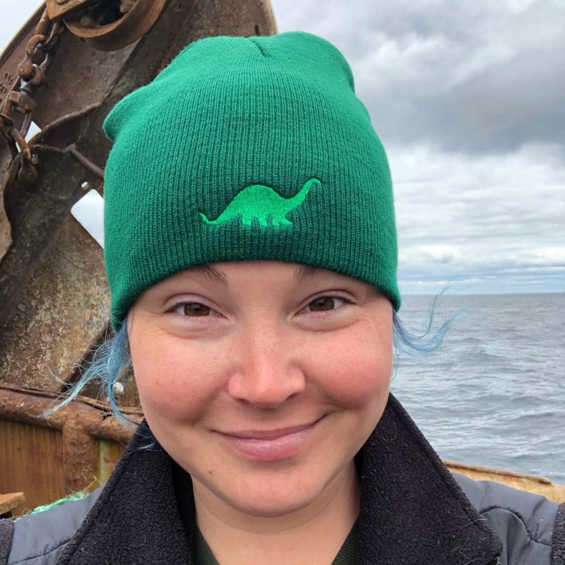 Maura Flynn in green dino hat onboard fishing vessel. 