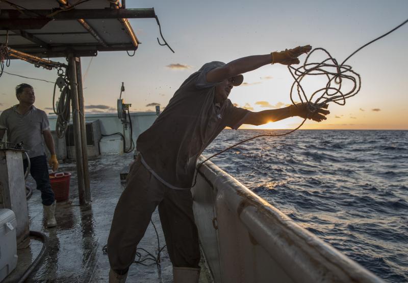 A man throw a rop off the side of a boat 