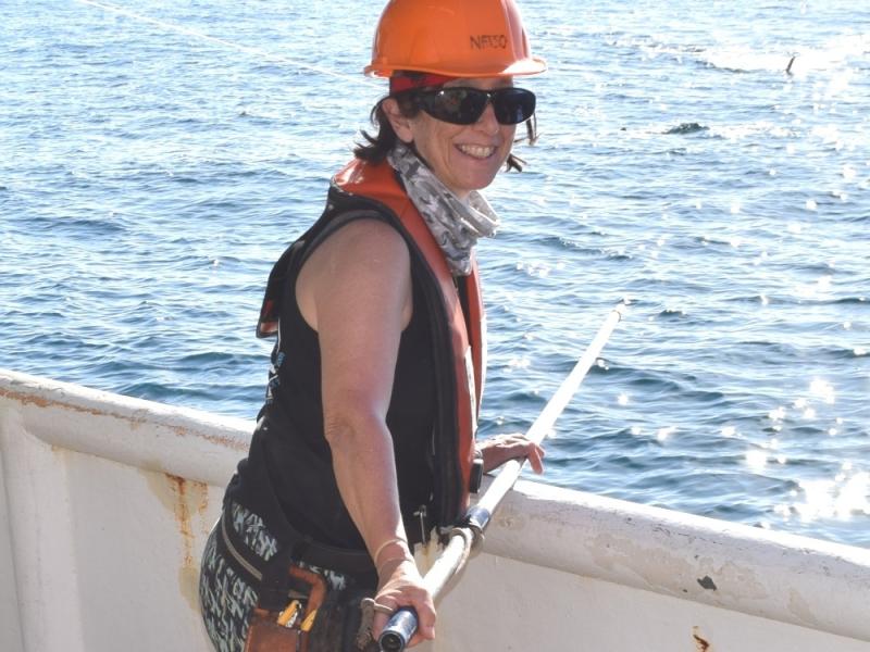 Lisa Natanson in hard hat and safety gear with shark tagging pole. 