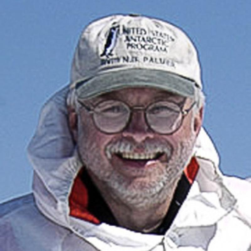 Portrait of man with glasses, white hat and white jacket with blue sky in the background