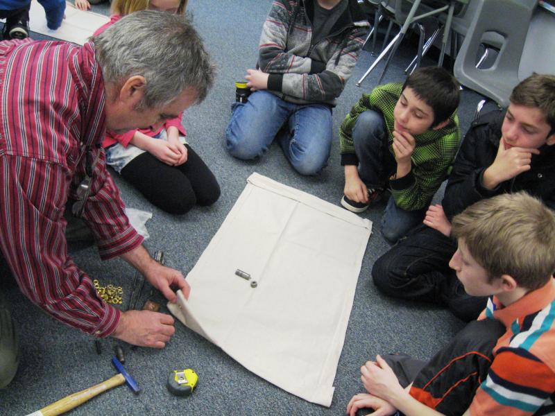 Adult surrounded by young students showing how to build a drifter.