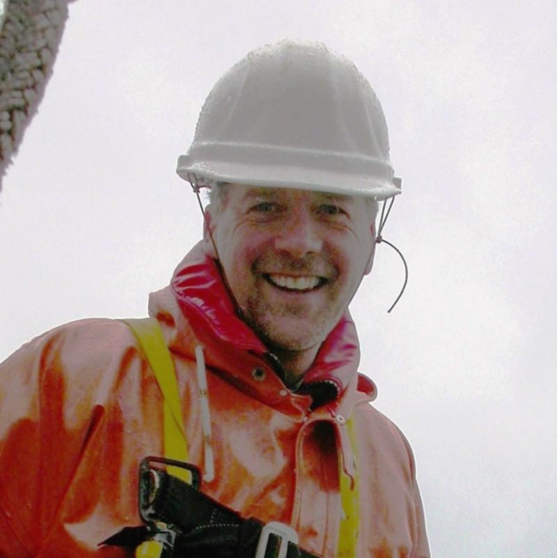 Man with white helmet and orange suit with cloudy sky behind him