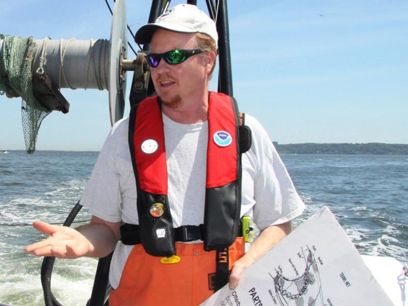 John Rosendale at the stern of Navoo with pfd and chart.
