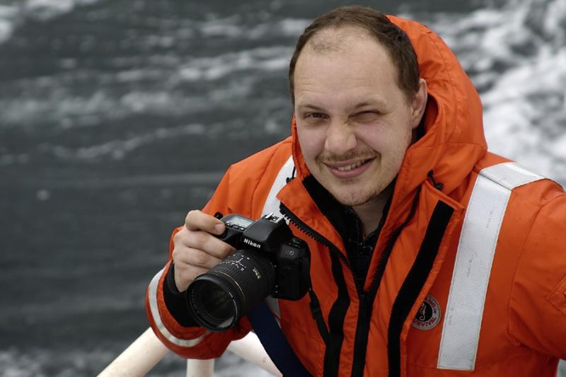 Man wearing orange coat holding up a camera