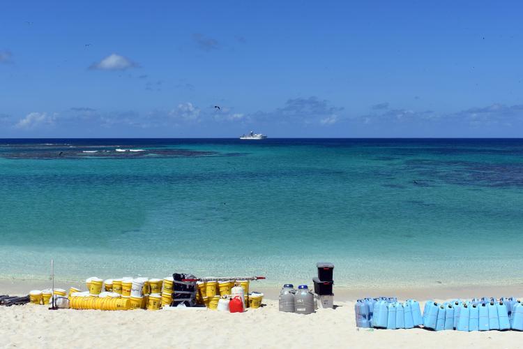 A photo taken from a beach on Laysan Island field camp supplies staged before the pick-up by NOAA ship (seen on the horizon).