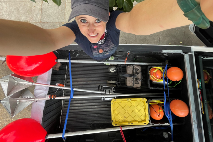 Anne standing in the bed of a pickup truck loaded with drifting buoys for the ACCESS team. Credit: NOAA Fisheries/Anne Simonis.