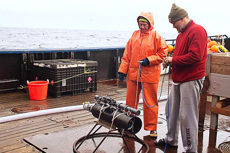 Scientists looking at scientific equipment on a boat