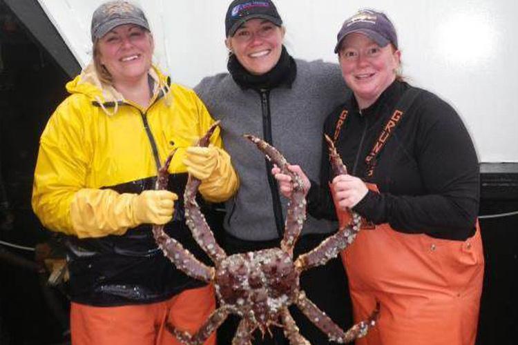 Three scientists holding up a large crab