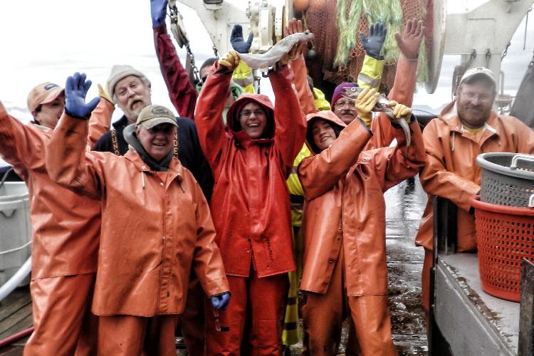 Group of scientists in orange suits waving and smiling at the camera