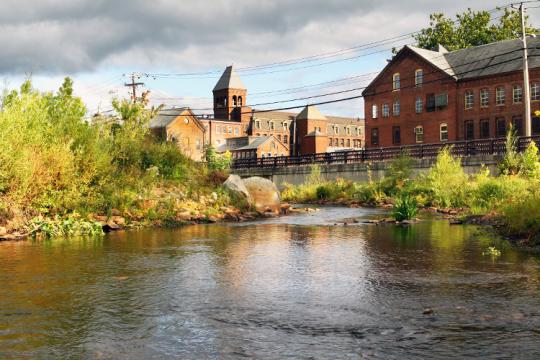 A river flows past several historic brick buildings