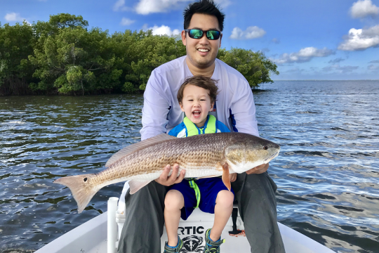 Anglers display a redfish from a boat.