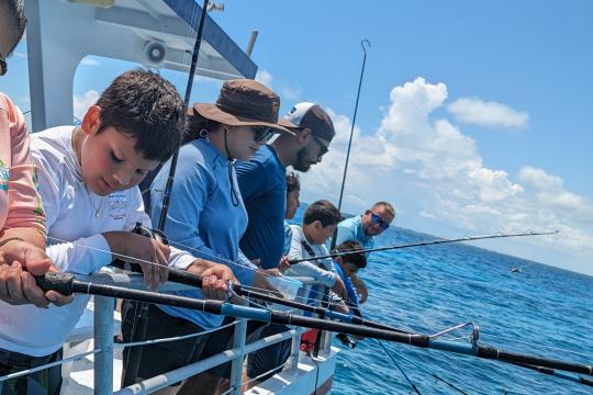 People fishing and looking over boat into water