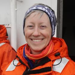 Photo of Katie Luxa wearing an orange flight suit.
