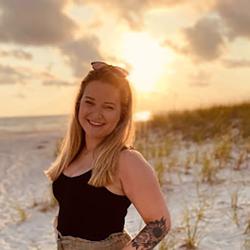 Megan Amico on the beach with sun set in the background.