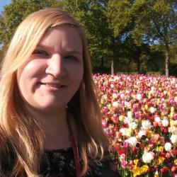 Female scientist stands in front of a field of colorful tulips.