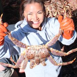 woman holding a crab in the hold of a fishing vessel.