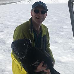 Man smiling and dog with snowy background