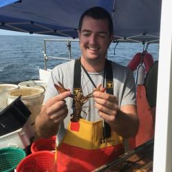 Thomas holding a lobster on the deck of a boat. 