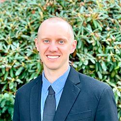 Portrait of scientist in a suit with green bushes in background
