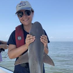 Katie in sunglasses holding shark during survey. 