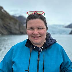 Portrait of scientist wearing blue coat with mountains and a lake in the background