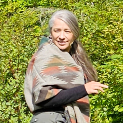 Melissa Mountcastle in long sleeved shirt with shawl walking in the woods.