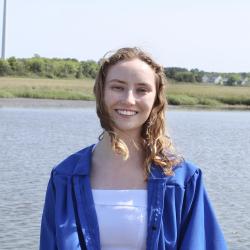 Renea Briner in white top and blue jacket by the water. 