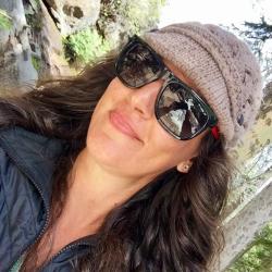 Brunette scientist with beige hat and glasses with hill in background