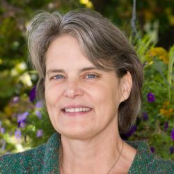 Portrait of brunette scientist with green sweater against a garden in the background
