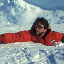 Brunette man wearing sunglasses with orange coat buried half way in snow