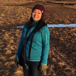 Maggie Chan standing in wetlands with mountains in the distance