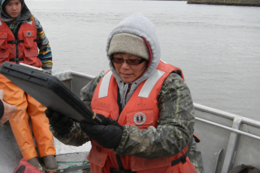 Photo of two technicians in a boat recording information on a tablet.