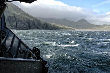 A view of Alaska's shores from the port side - a cloud hangs over the mountains