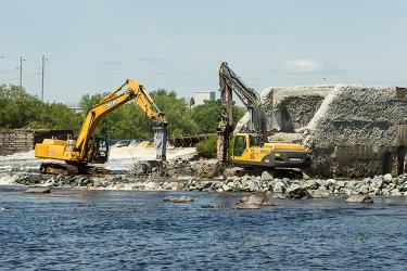 Two heavy construction machines demolish a dam