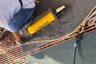 A man holds a yellow tube about 2 feet long