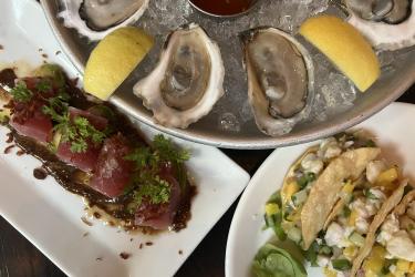 A seafood spread of oysters, tuna, and ceviche tacos